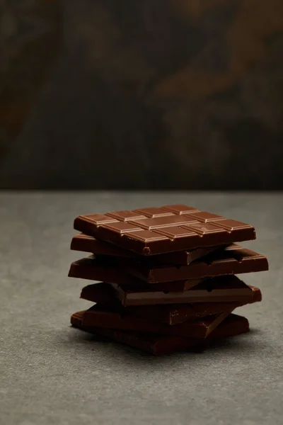 Vista de cerca de barras de chocolate apiladas sabrosas dulces sobre fondo gris - foto de stock