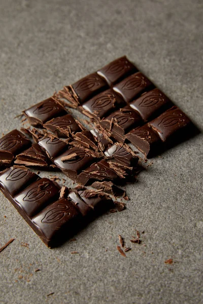 Close-up view of crashed gourmet bar of chocolate on grey — Stock Photo