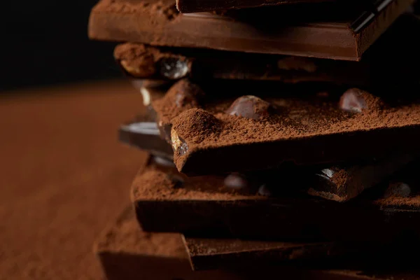 Vista close-up de deliciosas peças de chocolate com nozes e cacau em pó — Fotografia de Stock