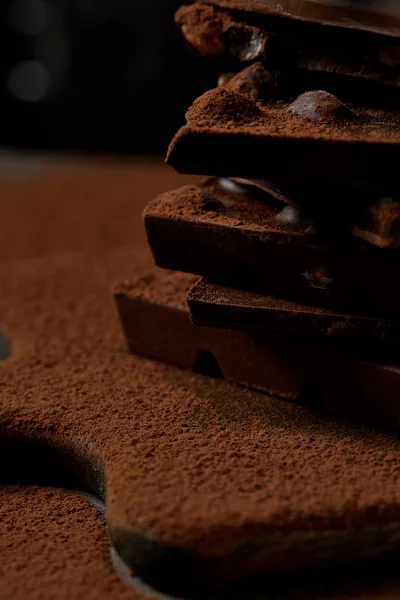 Vista ravvicinata di deliziosi pezzi di cioccolato con noci e cacao in polvere sul tagliere — Foto stock