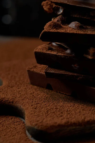 Close-up view of delicious chocolate pieces with nuts and cocoa powder on chopping board — Stock Photo