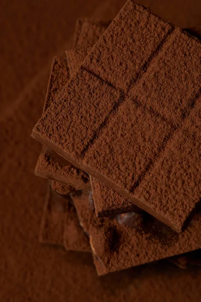 Vista de perto de pedaços de chocolate gourmet doce e cacau em pó — Fotografia de Stock