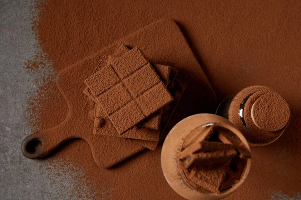 Top view of tasty chocolate pieces with cocoa powder on chopping board — Stock Photo