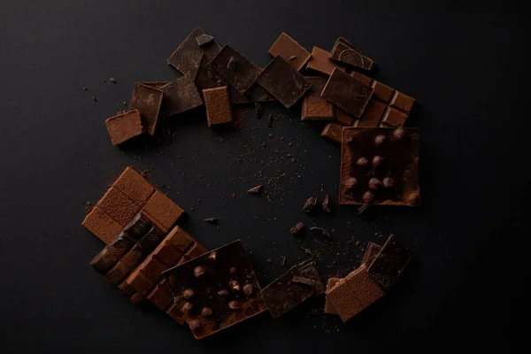 Vista dall'alto di pezzi di cioccolato gourmet assortiti su sfondo nero — Foto stock