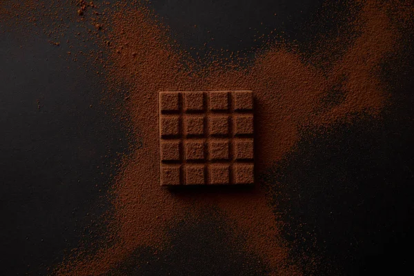 Ansicht von süßer Schokolade und Kakaopulver auf schwarzem Hintergrund — Stockfoto