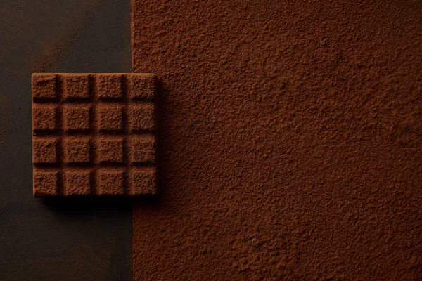 Vue de dessus de délicieux cacao brun en poudre et chocolat savoureux sur fond noir — Photo de stock