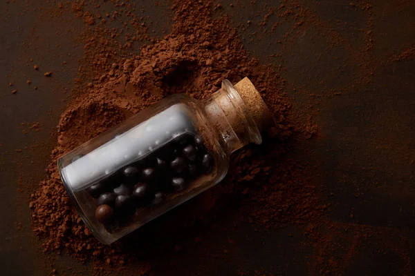 Vista superior de deliciosas bolas de chocolate em frasco de vidro e cacau em pó em marrom — Fotografia de Stock