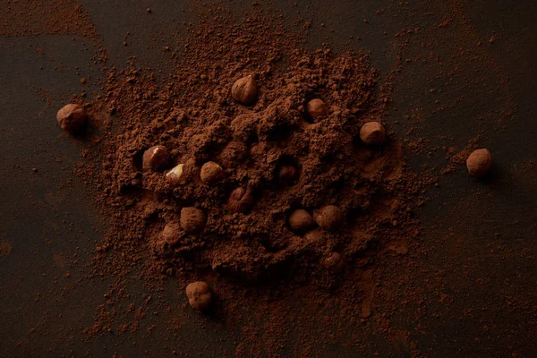 Vue de dessus de cacao gourmet en poudre et noisettes sur fond sombre — Photo de stock