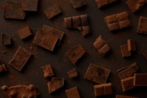 Vista superior de deliciosas peças de chocolate no fundo preto — Fotografia de Stock