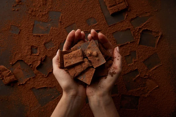 Tiro recortado de deliciosos pedaços de chocolate em mãos humanas — Fotografia de Stock