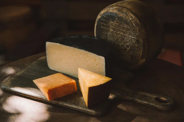 Различные сорта вкусного сыра на деревенском деревянном столе — стоковое фото