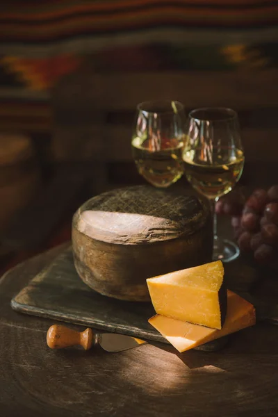 Rebanadas delicioso queso con vino y uvas en tabla de cortar de madera - foto de stock