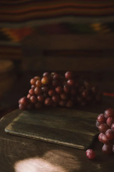 Close-up shot of red grapes on rustic wooden table — Stock Photo
