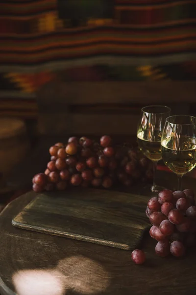 Nahaufnahme von Gläsern mit Weißwein und Trauben auf rustikalem Holztisch — Stockfoto