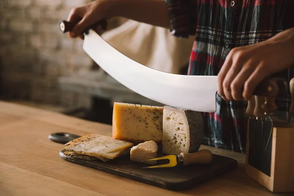 Plan recadré de femme coupant délicieux fromage avec couteau à double poignée — Photo de stock