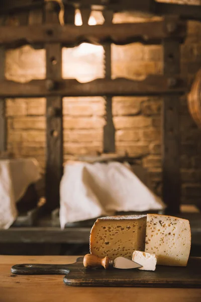 Delicacy sliced cheese with knife on wooden cutting board — Stock Photo