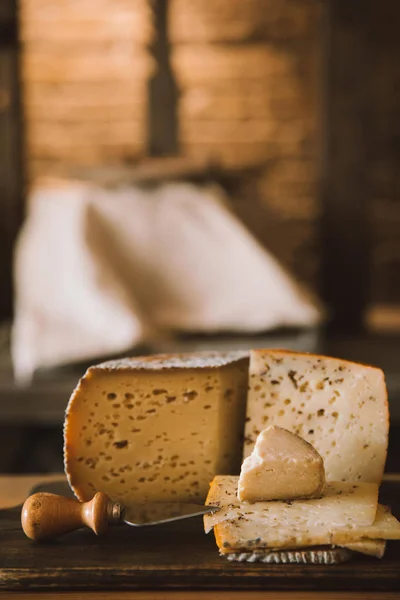 Primer plano de delicioso queso en rodajas con cuchillo en tabla de cortar de madera - foto de stock