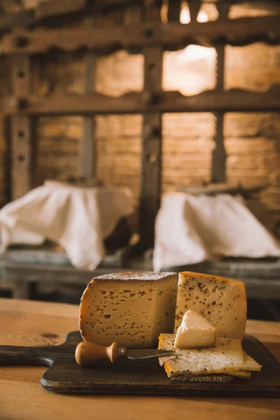 Delicioso queso en rodajas con cuchillo en tabla de cortar de madera - foto de stock