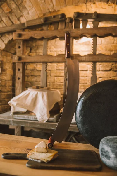 Cabeça de queijo redondo grande com faca de punho duplo na mesa de madeira — Fotografia de Stock