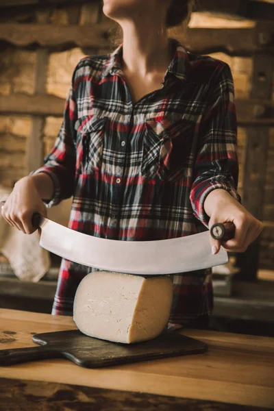 Foto recortada de mujer cortando queso con cuchillo de doble mango - foto de stock