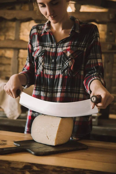 Giovane donna che taglia formaggio con doppio coltello maneggiato — Foto stock