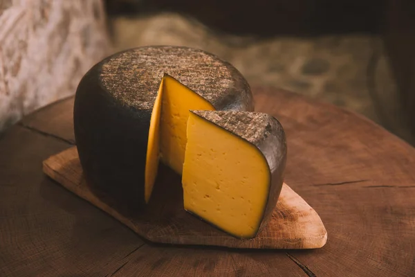 Delicioso queso en rodajas sobre tabla de cortar de madera rústica - foto de stock