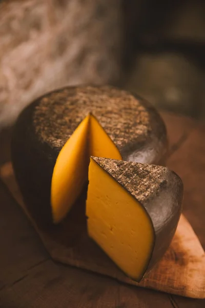 Primo piano di formaggio tagliato a fette su tagliere in legno rustico — Foto stock