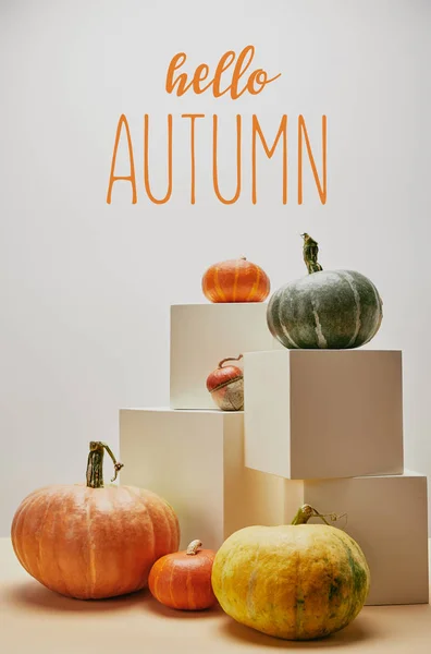 Autumnal decoration with orange, yellow and green pumpkins on cubes and table with HELLO AUTUMN lettering — Stock Photo