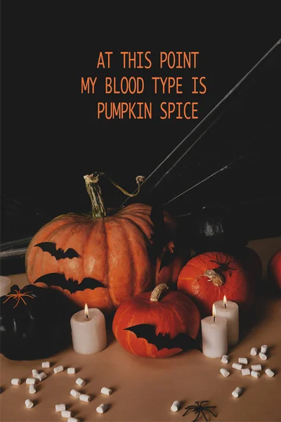 Zucche, pipistrelli di carta, ragno e ragnatela sul tavolo con la scritta di Halloween 