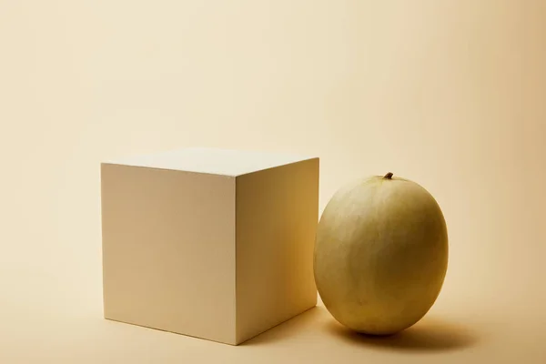 Primer plano de melón maduro y cubo en la superficie beige - foto de stock