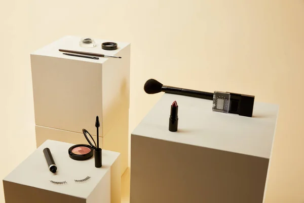 Various makeup accessories kit on beige cubes — Stock Photo