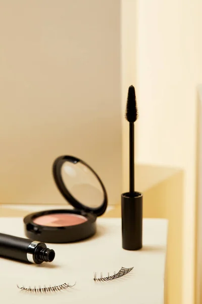 Close-up shot of mascara with false eyelashes and shimmer on beige — Stock Photo