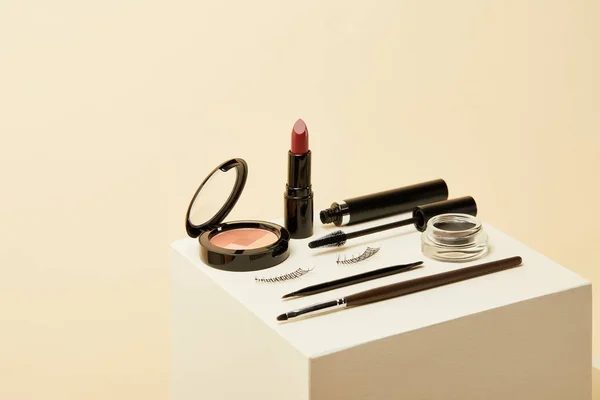 Close-up shot of makeup supplies kit on beige cube — Stock Photo