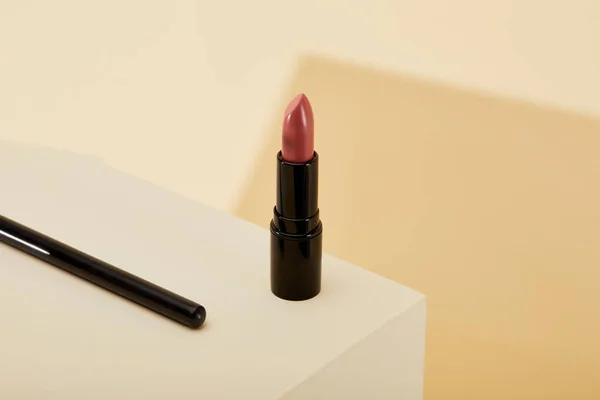 Close-up shot of lipstick standing on beige surface — Stock Photo