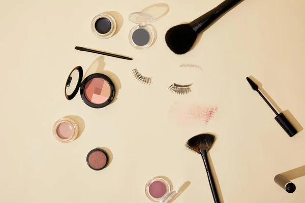 Top view of various cosmetics lying on beige surface — Stock Photo