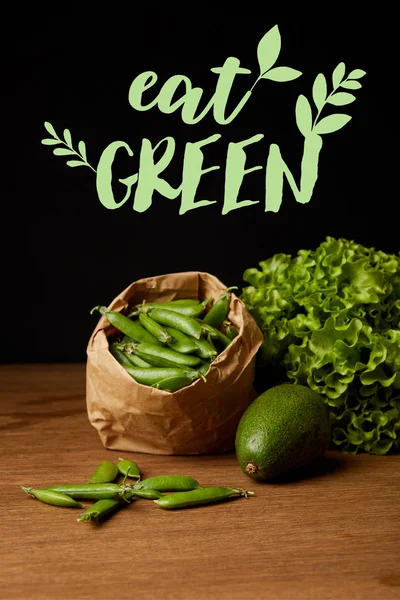 Close-up shot of avocado, green peas and lettuce on wooden surface with 