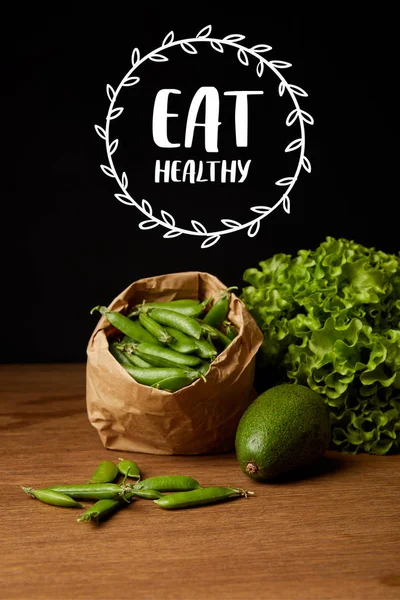 Close-up shot of avocado, green peas and lettuce on wooden surface with 