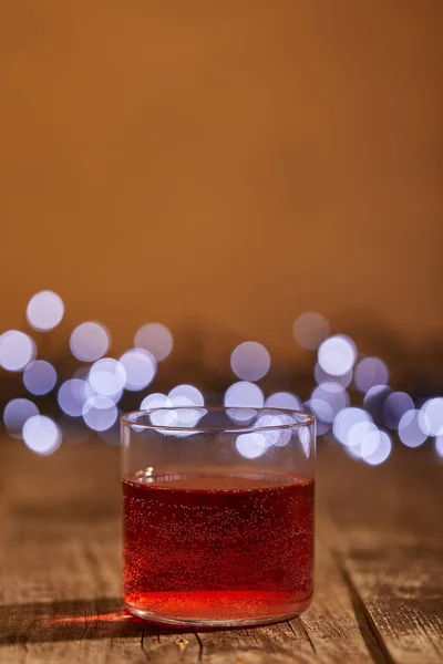 Vue rapprochée du vin chaud savoureux en verre sur la surface en bois avec des lumières bokeh déconcentrées sur fond — Photo de stock