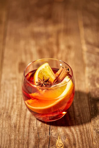 Vista de perto da bebida quente de vinho quente com pedaços de laranja e estrelas de anis na mesa de madeira — Fotografia de Stock