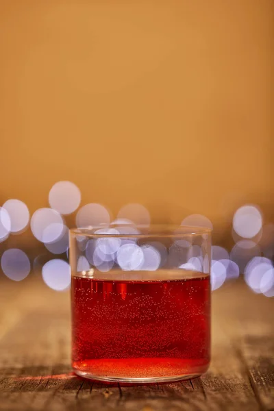 Vista ravvicinata di gustoso vin brulè in vetro su superficie di legno con luci bokeh sfocate sullo sfondo — Foto stock