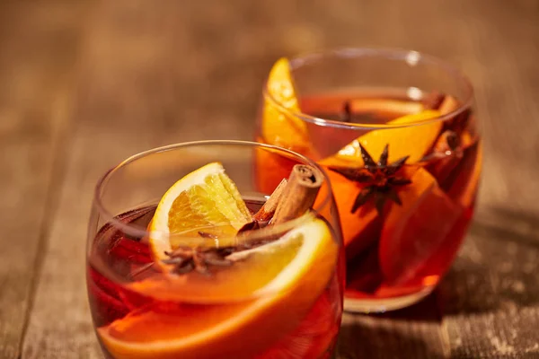Close up view of mulled wine in glasses with orange pieces and spices on wooden tabletop — Stock Photo