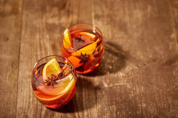 Близкий вид на вкусные горячие напитки глинтвейна с апельсиновыми кусочками на деревянном столе — стоковое фото