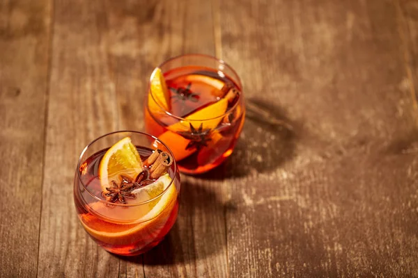 Vista de cerca de deliciosas bebidas de vino caliente con especias con trozos de naranja en la mesa de madera - foto de stock