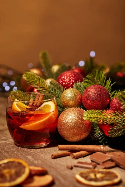Close up view of mulled wine drink in glass and pine tree with christmas toys on wooden surface — Stock Photo