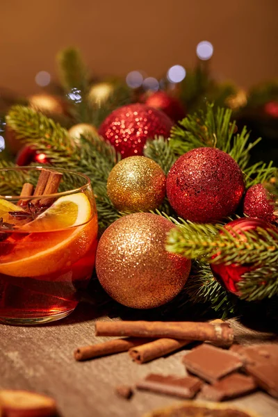 Vue rapprochée de la boisson au vin chaud en verre, chocolat et pin avec des jouets de Noël sur la surface en bois — Photo de stock