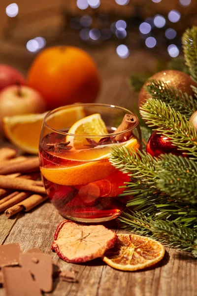 Vue rapprochée de savoureux vin chaud boisson avec des morceaux d'orange et d'épices sur la surface en bois avec des lumières bokeh sur fond — Photo de stock