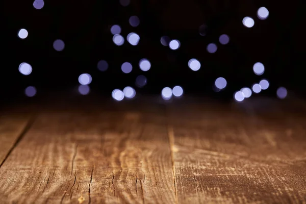 Close up view of wooden tabletop and defocused bokeh lights backdrop — Stock Photo