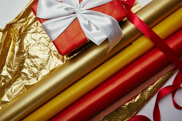Top view of present with ribbon and bright wrapping papers on white backdrop — Stock Photo