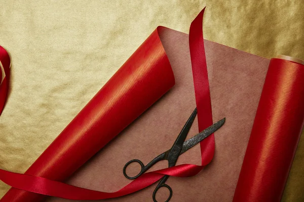 Top view of ribbon and scissors on red and golden wrapping papers background — Stock Photo