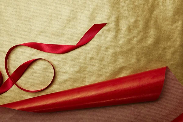 Vista superior da fita em vermelho e dourado papel de embrulho fundo — Fotografia de Stock